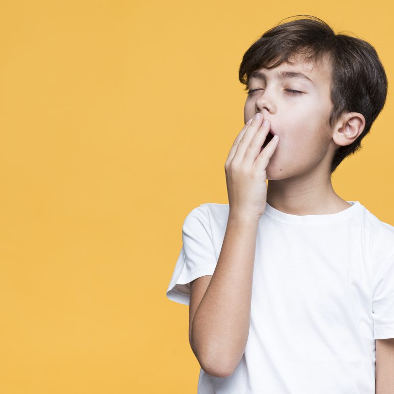 sleepy young boy yellow background